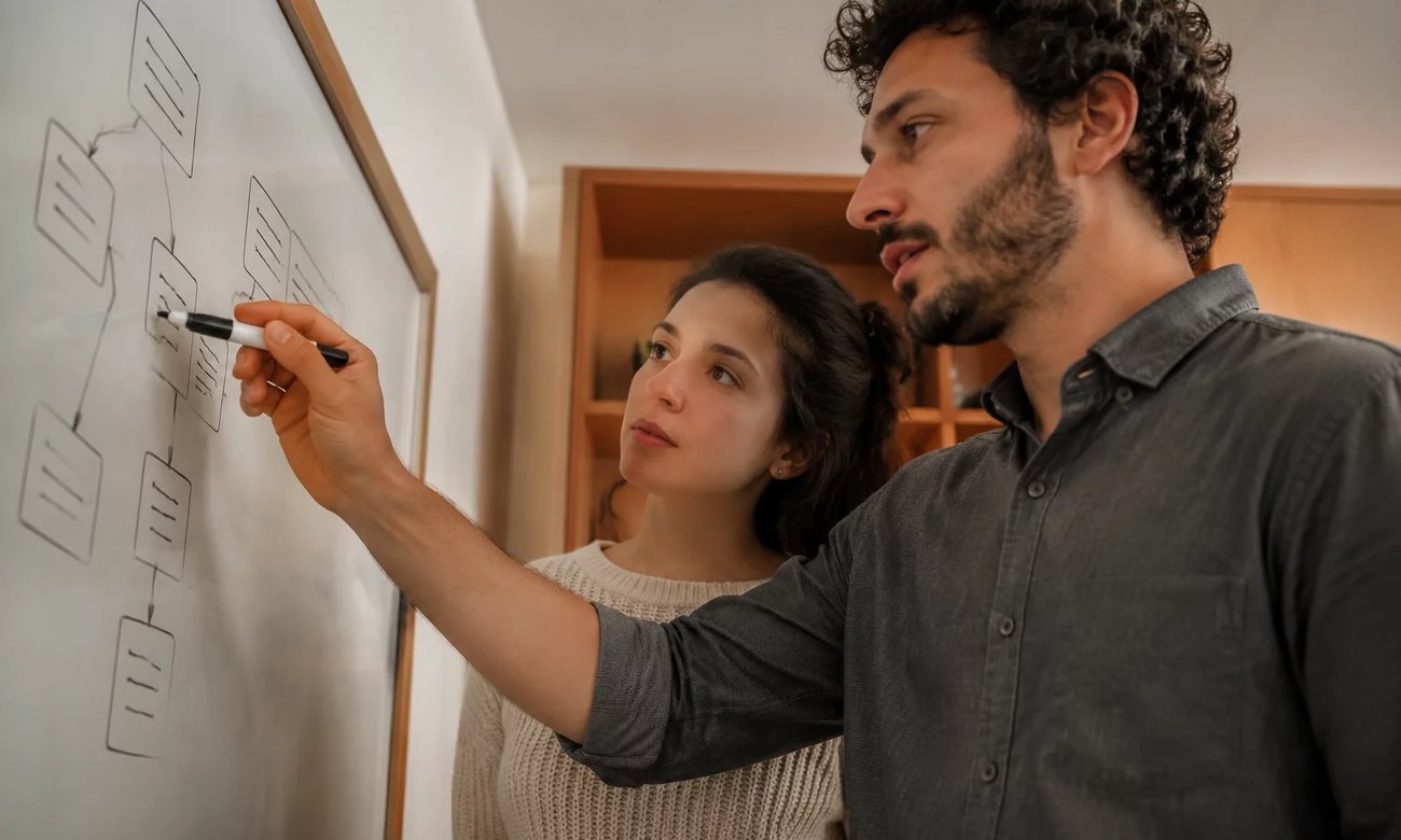 Grupo em sala clara acompanhando a explicação de uma participante que fala de pé